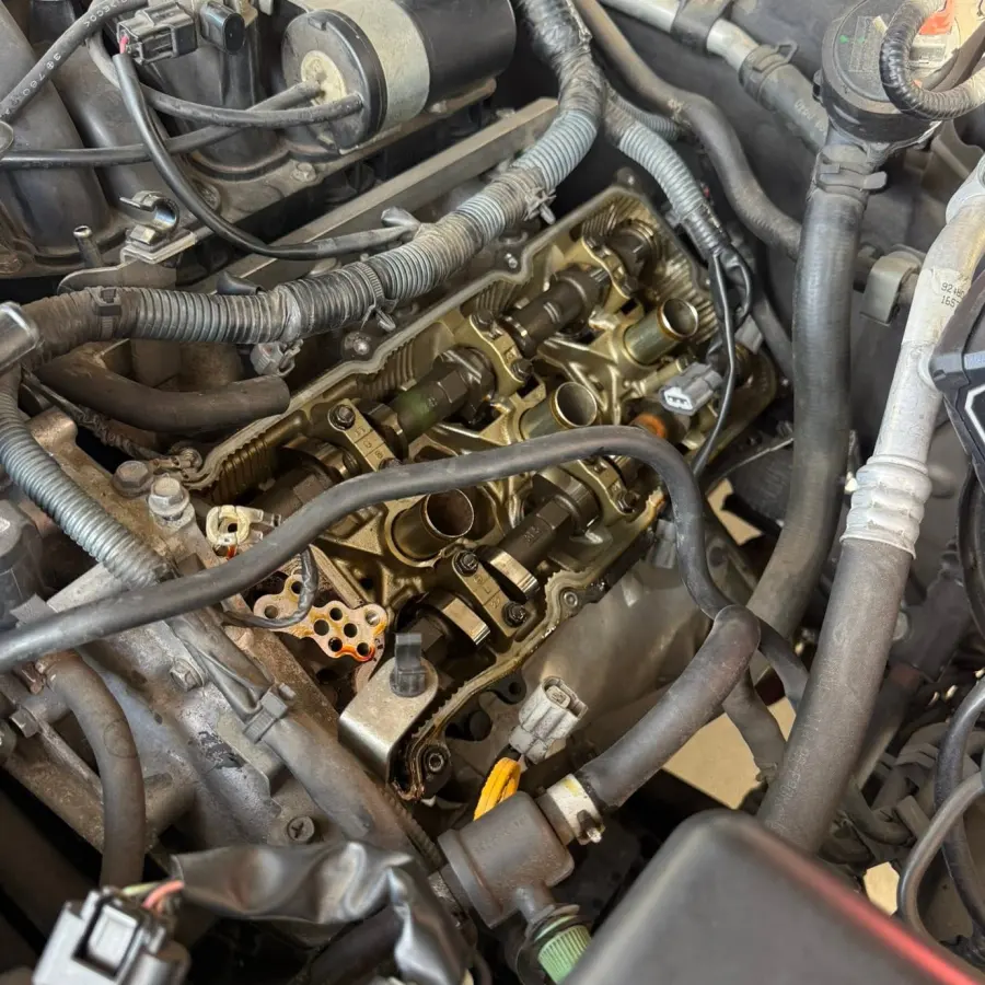 Engine bay with the valve cover removed during an on-site repair