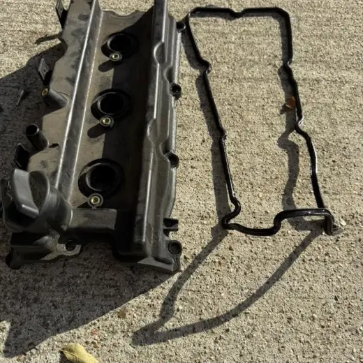The old leaking valve cover and gasket laid out on the driveway